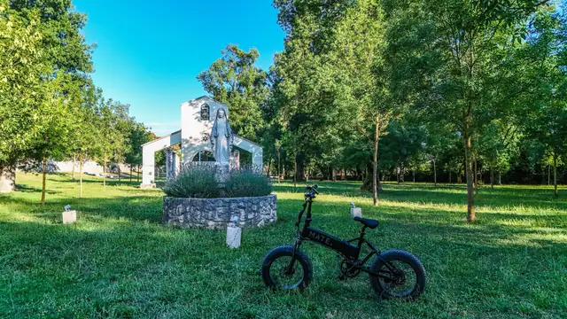 Mate.Bike in a park by a chapel and a statue of Our Lady